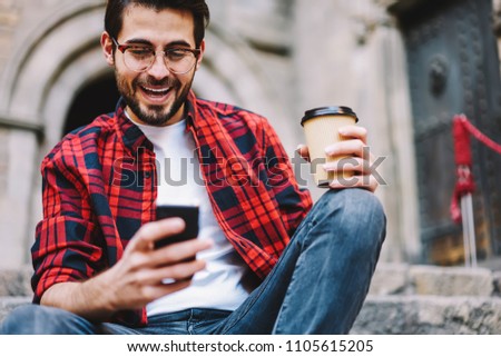 Excited millennial male getting message about victory in online lottery surprised with achievement outdoors, overjoyed young hipster guy happy about getting credit in banking via smartphone app