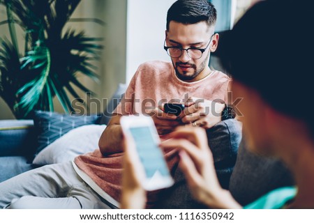Addicted boyfriend and girlfriend ignoring live communication while chatting in social networks on modern smartphones using wireless 4G internet at home interior.Marriage messaging online on cellulars