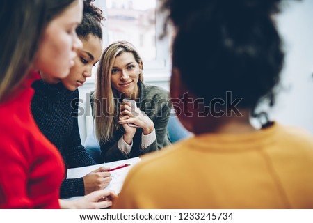 Cropped image of female multiracial crew of designers cooperating on productive job, positive blonde girl listening to colleagues idea during brainstorming session and communication on meeting