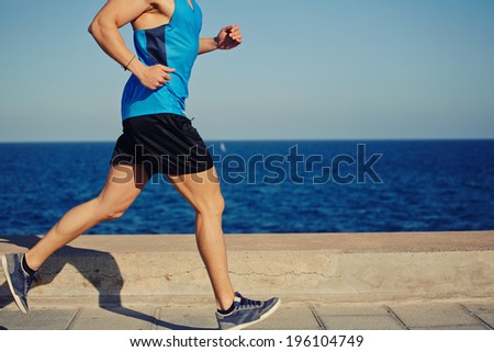 Strong male jogger running along the sea en action