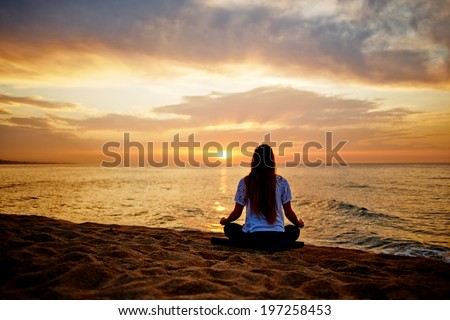 Silhouette of a girl in a sitting yoga pose in the evening sunset