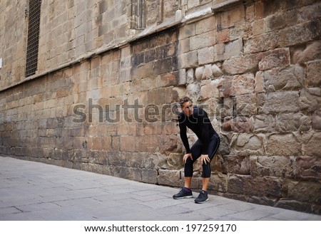 Handsome sportsman tired morning jog rest resting against the wall