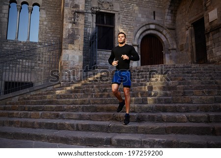 Attractive male jogger runs down the stairs and looking away