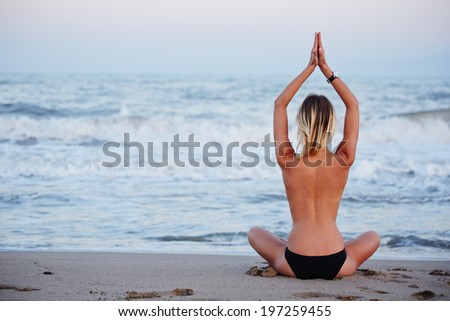 Yoga on the beautiful beach performed by attractive young girl, evening spiritual training