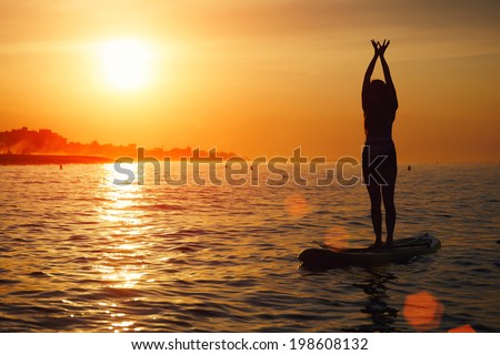 Silhouette of paddle surf yoga at the amazing sunset over the sea, spiritual yoga meditation on the beach