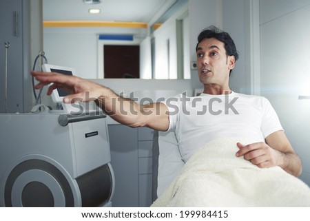 Handsome male patient showing with the hand, talking to the doctor in the room of aesthetic clinic