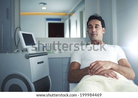 Male patient relaxing after aesthetic procedure in room of aesthetic clinic