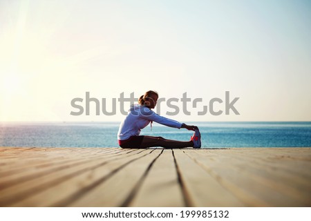 Beautiful female jogger doing workout during the morning training on the beach,workout before the morning jog along the seafront