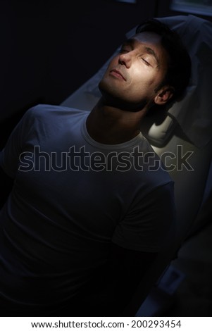 Attractive man at the facial rejuvenation procedure lying on the medical chair in cabinet of aesthetic clinic