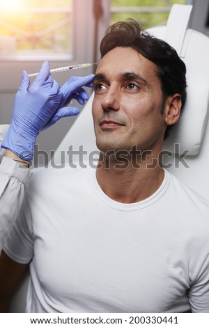 Beautiful man getting cosmetic injection to the face, remove wrinkles