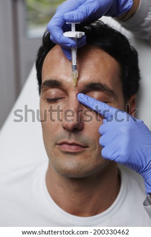 Adult man getting wrinkles removed in face with syringe, rejuvenating in aesthetic clinic