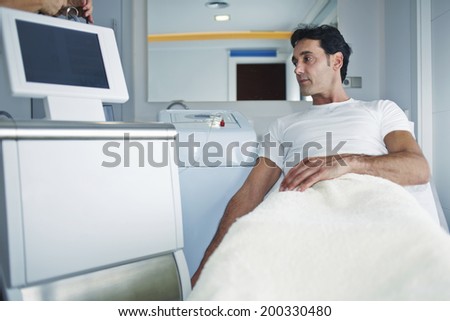 Attractive male patient lying on the medical chair in the cabinet of aesthetic clinic