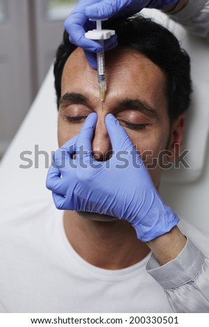 Attractive adult man getting injection to remove eye wrinkles, rejuvenating in aesthetic clinic