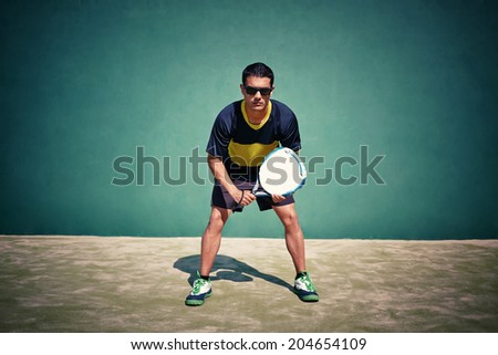 Athletic sportsman ready to feed ball in paddle game on beautiful court background, paddle game outside, healthy lifestyle concept