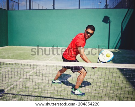 Athletic sportsman ready to feed ball in paddle game on beautiful court background, paddle game outside