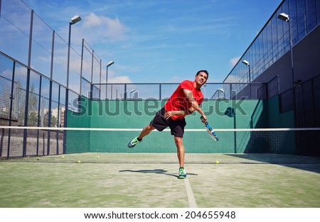 Attractive man in bright sportswear with racket in the hands feed ball in paddle game, paddle game outside, healthy lifestyle concept