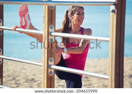 Beautiful woman with muscular body doing stretching exercise on horizontal bar, sport outdoor, fitness and healthy lifestyle concept