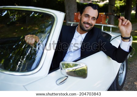 Attractive handsome and successful man driving cabriolet classic car and smiling at the camera, lifestyle and successful business concept