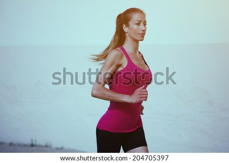 Attractive female runner with beautiful figure runs with speed along the wall of pastel colors,  healthy lifestyle and fitness concept