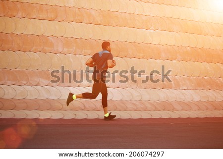 Healthy build sportsman running in the park at soft sunset light, evening run at beautiful sunset, male jogger running outdoors, fitness and healthy lifestyle concept