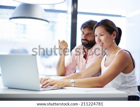 Group of successful business people having meeting together, two colleagues working together in the office, young man and woman sitting with laptop computer and have a discussion