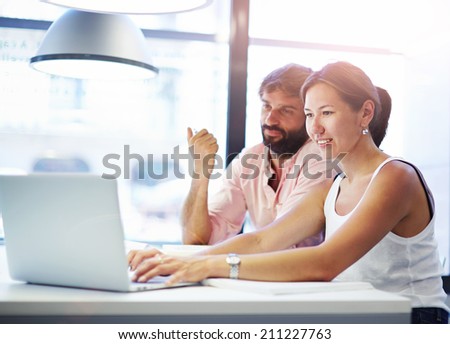 Students sitting at a table in a library while learning and working on a laptop, teenagers watching something on laptop in library in college, studying and education concept