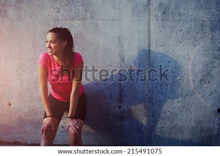 Fitness sport girl resting after intensive evening run, young attractive runner taking break after jogging outdoors, female jogger in bright sportswear smiling looking away, advertising for sports