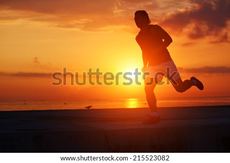 Jogger running with high speed, silhouette of male runner in action running along the beach at colorful sunrise, beautiful runner with muscular body, fitness and healthy lifestyle concept