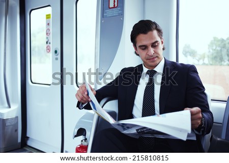 Businessman reading newspaper in metro train, handsome man reading a newspaper,  man in suit seated read big newspaper, businessman going to work