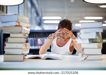 Stressed student of high school sitting at the library desk, tired and bored to study asian student girl preparing to the exams, female student with pile of books study hard for exam in high school