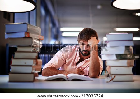 Frustrated college male student studying poorly at late evening, night before exam, male student with pile of books study hard for exam in high school, tired and bored to study hard for exam