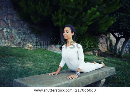 Woman with slim body making stretching yoga exercise, attractive young girl with beautiful body practicing yoga in green park, young beautiful woman making yoga outdoors