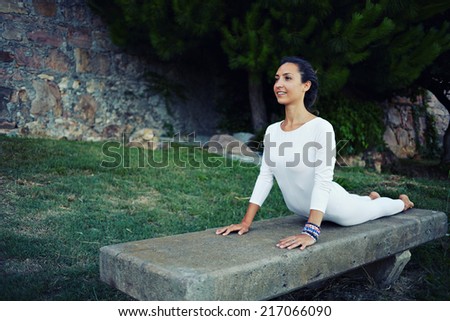 Healthy woman in white clothes meditating and exercising yoga, attractive woman with slim body making stretching yoga exercise outdoors,beautiful woman practicing the cobra pose in yoga