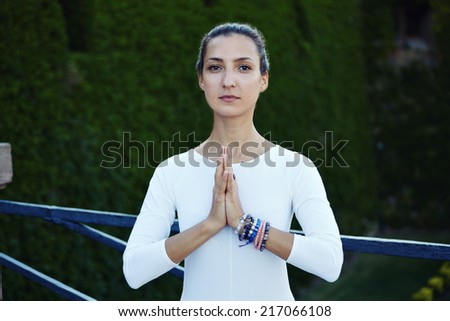 Portrait of a pretty brunette woman makes morning meditation outdoors, happy young woman looking for the camera and engage yoga outdoors, portrait of healthy woman relaxing in yoga pose