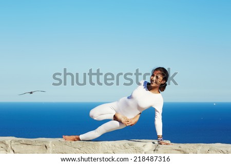 Pretty and beautiful girl smiling during yoga class outdoors, young healthy woman with beautiful figure makes yoga pose o high altitude with amazing view of sea on background,feeling healthy with yoga