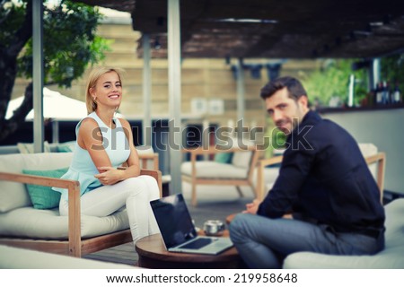 Successful business team of two people sitting outdoors in lounge terrace and planning work, businessman and businesswoman meeting in modern place outdoors, business partners having meeting outdoors