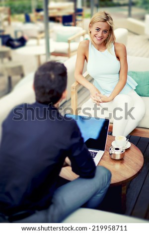 Attractive businesswoman smiling to the camera sitting on the chair in beautiful lounge bar terrace, happy businesswoman at  business meeting outdoors, business lunch in modern lounge bar cafe