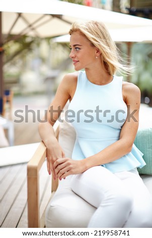 Pretty businesswoman sitting at cafe at business meeting outdoors, young professional female business woman sitting outdoors in cafe looking out, business woman having meeting outdoors