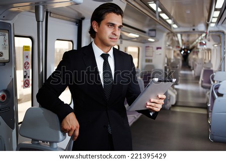 Handsome businessman working with tablet on the way to work, young executive going in train, businesspeople using technology for work, business man using the new media technologies and devices