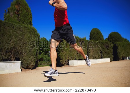 Fitness man running outdoors with high speed, male legs and shoes in action, male athlete fitness runner sprinting fast outside at sunny summer day, sports fitness concept