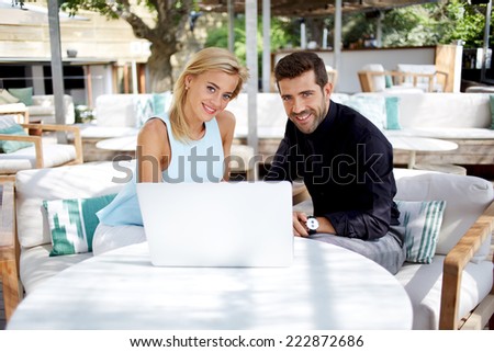 Young businessman discussing plan with female colleague, businesspeople working with laptop sitting in modern place, business meeting of two colleagues outside the office, business and success concept