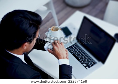 Businessman watching the time in his wear watches,brunette businessman checking the time on his wrist watch, executive looking at the time on his wrist watch, man sitting at table  at business meeting