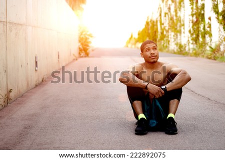 male athlete resting after cross fit exercise, sittinig on the road