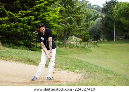 Golfer on sand trap hitting golf ball to the hole, rich adult man playing golf, strong golf shot in action,wealthy man at recreation playing golf on green course,golfer hitting ball in action
