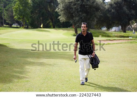 Golf player carrying his bag and walking on a sunny day at golf course,confident man at golf game walk on beautiful golf course holding bag and driver,professional golf player walking to the next hole