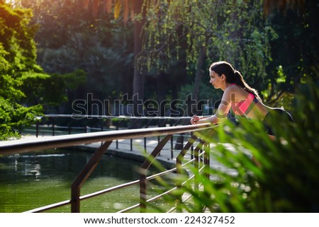 Young athletic woman resting after intensive morning jog in the park, perfect sunny day for sport outdoors, fit woman in bright sportswear taking a break after jog in beautiful park, fitness sport