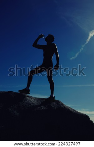 Muscular build beautiful man drinking water after fitness exercise outdoors, athlete refreshing with bottle of water after running