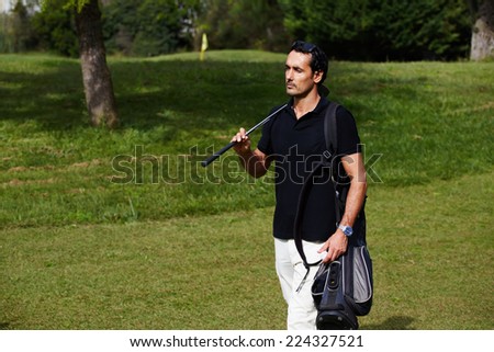 Confident rich man at golf game on holidays walk on beautiful green golf course holding bag and driver, success and welfare concept, male golfer walking to the next hole, golfer walking to next hole