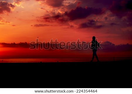Dark silhouette of running man with sunrise at early morning, male runner with muscular body at fitness training jogging on the beach