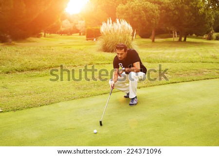 Professional golf player looking trajectory of the ball on beautiful golf course, golfer standing on the course preparing to hit golf ball to the hole